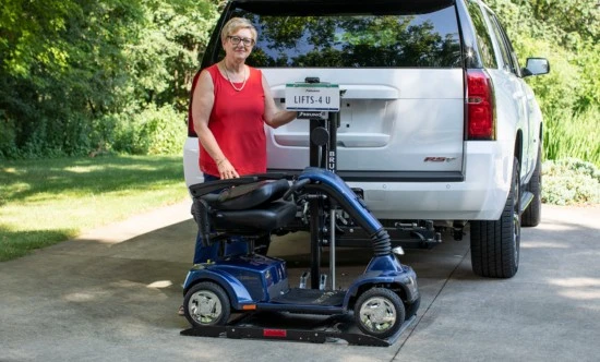 a women standing behind a scooter lift that's attached to a white suv