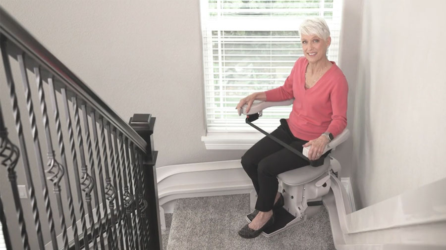 woman riding bruno stairlift up curved staircase