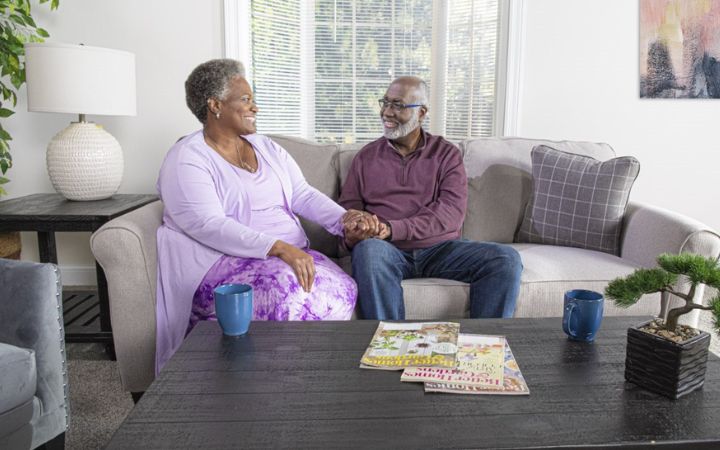 happy couple holding hands while sitting on a couch