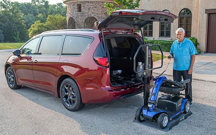 Bruno scooter lift on the back of an SUV next to a mobility device user